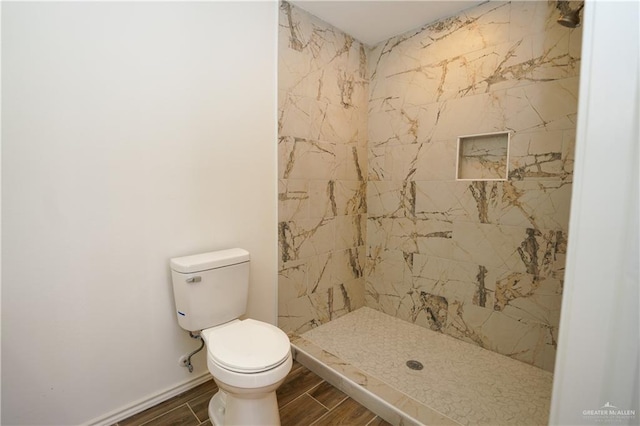 bathroom featuring tiled shower and toilet