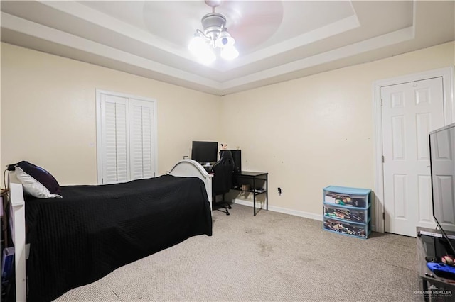 carpeted bedroom with a tray ceiling and ceiling fan