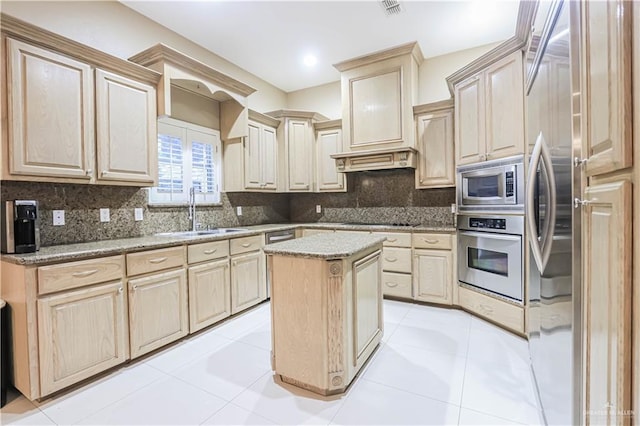 kitchen with sink, decorative backsplash, light brown cabinetry, a kitchen island, and stainless steel appliances