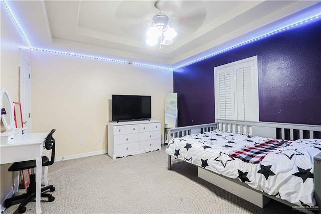 bedroom featuring a raised ceiling, ceiling fan, and carpet flooring