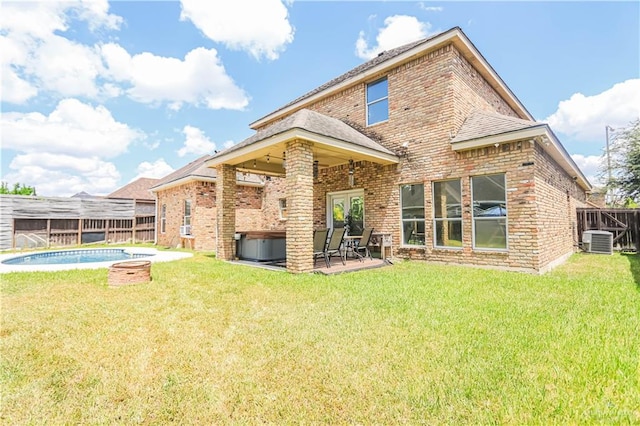 back of property with central AC, a yard, a patio, and a pool with hot tub