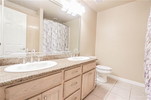 bathroom with toilet, vanity, and tile patterned floors