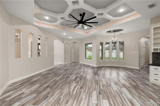 unfurnished living room with beamed ceiling, ceiling fan with notable chandelier, light hardwood / wood-style floors, and coffered ceiling