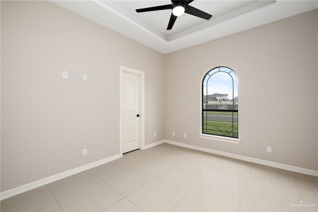 tiled empty room with a tray ceiling and ceiling fan