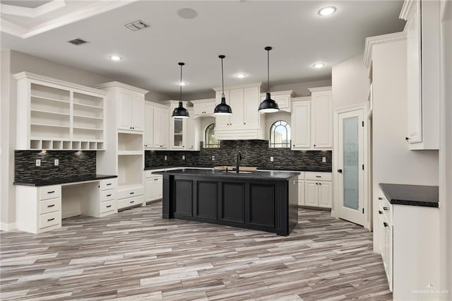 kitchen with a center island with sink, white cabinetry, hanging light fixtures, and light hardwood / wood-style floors