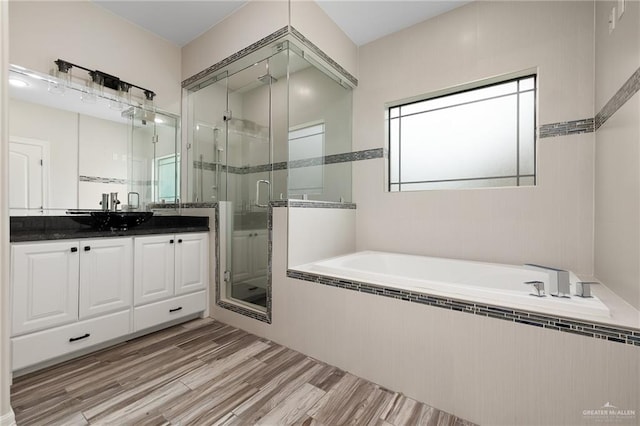 bathroom with hardwood / wood-style flooring, vanity, and shower with separate bathtub