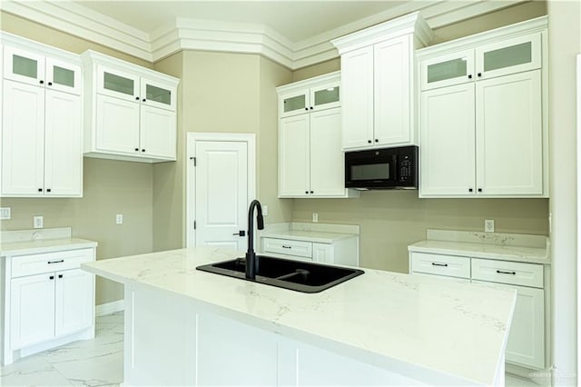 8801 Swan Lake Dr, Harlingen, TX 78550 - kitchen with black microwave, a sink, white cabinetry, marble finish floor, and a center island with sink