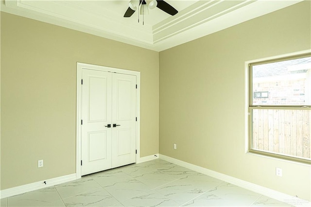 8801 Swan Lake Dr, Harlingen, TX 78550 - unfurnished bedroom featuring a closet, a tray ceiling, marble finish floor, and baseboards