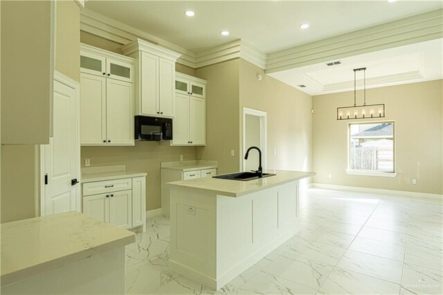 8801 Swan Lake Dr, Harlingen, TX 78550 - kitchen with marble finish floor, a center island with sink, a sink, black microwave, and baseboards