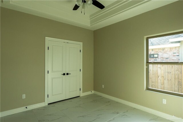 8801 Swan Lake Dr, Harlingen, TX 78550 - unfurnished bedroom featuring marble finish floor, a closet, a raised ceiling, a ceiling fan, and baseboards