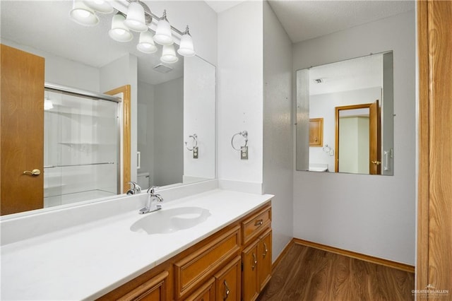 bathroom featuring hardwood / wood-style floors, vanity, toilet, and an enclosed shower