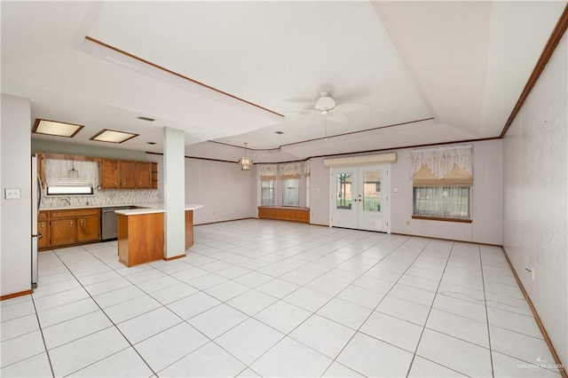 kitchen with ceiling fan, backsplash, kitchen peninsula, a tray ceiling, and appliances with stainless steel finishes