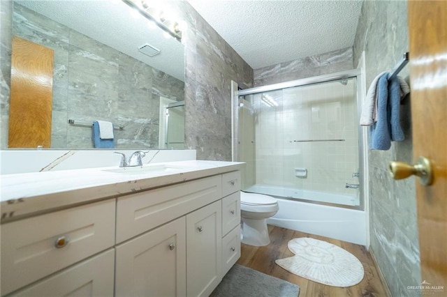 6913 N 31st St, Mcallen, TX 78504 - bathroom featuring a textured ceiling, vanity, combined bath / shower with glass door, wood finished floors, and tile walls