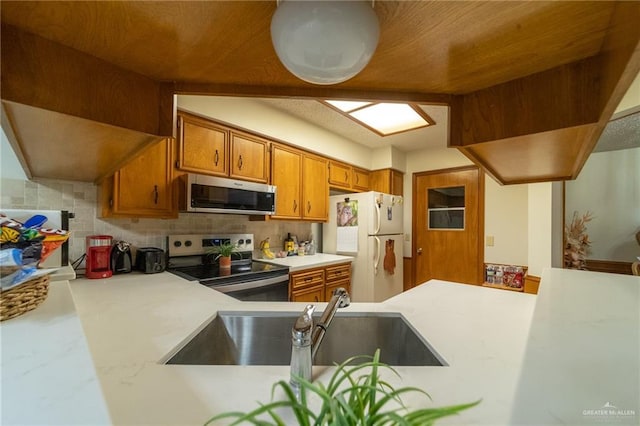 6913 N 31st St, Mcallen, TX 78504 - kitchen featuring appliances with stainless steel finishes, brown cabinetry, light countertops, and tasteful backsplash
