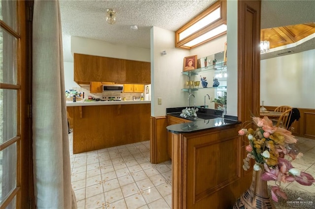 6913 N 31st St, Mcallen, TX 78504 - indoor wet bar featuring stainless steel microwave, wainscoting, light floors, and a textured ceiling