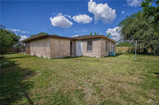 rear view of house featuring cooling unit and a lawn