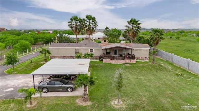 rear view of property with fence, a yard, and a carport