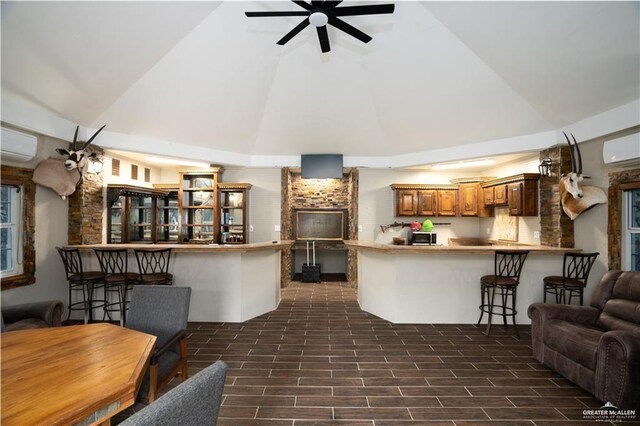 living area featuring high vaulted ceiling, an AC wall unit, a wall mounted air conditioner, ceiling fan, and a fireplace