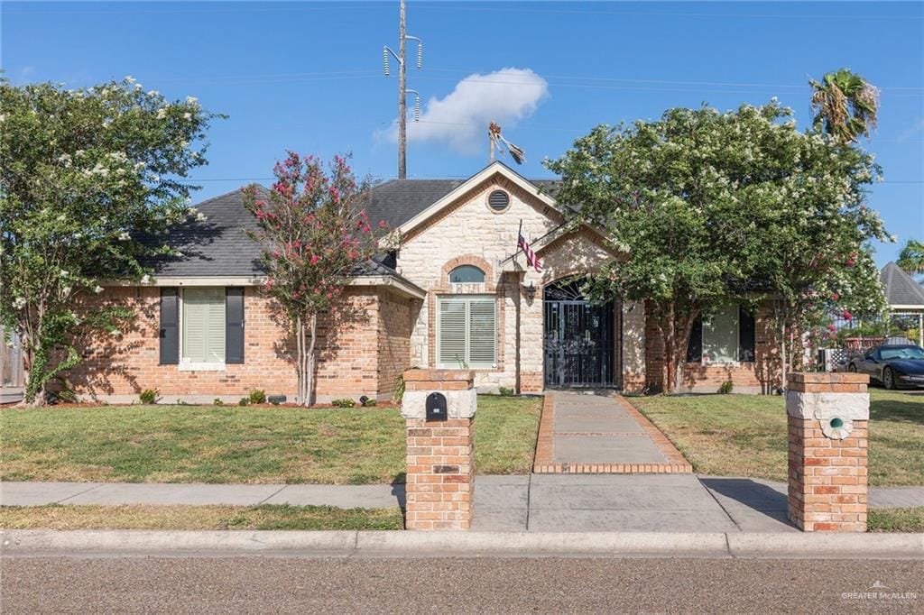 705 Amethyst Dr, Weslaco, TX 78596 - french country home with a front yard and brick siding