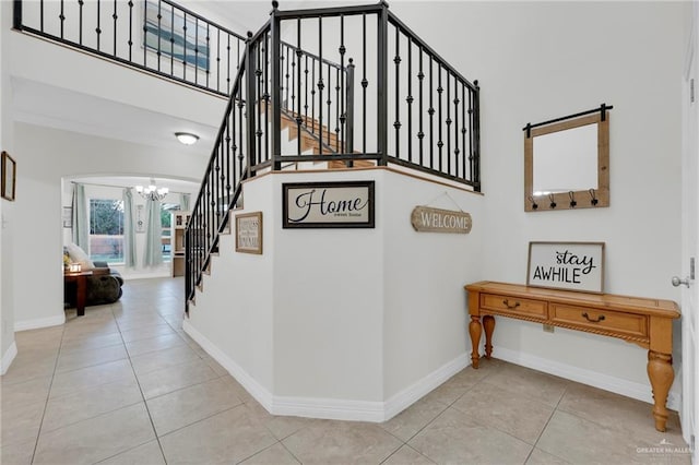 stairway featuring a chandelier, tile patterned flooring, a towering ceiling, and baseboards