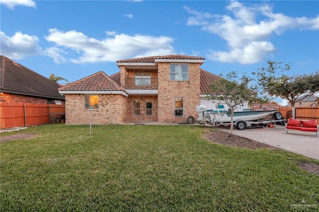 back of property featuring a lawn, a tile roof, a fenced backyard, and a balcony