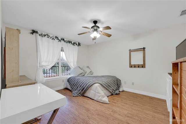 bedroom featuring a ceiling fan, light wood-type flooring, visible vents, and baseboards