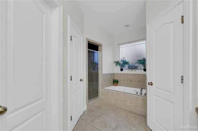 bathroom with a stall shower, a garden tub, and tile patterned floors