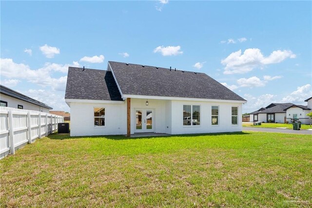 rear view of house featuring cooling unit and a lawn