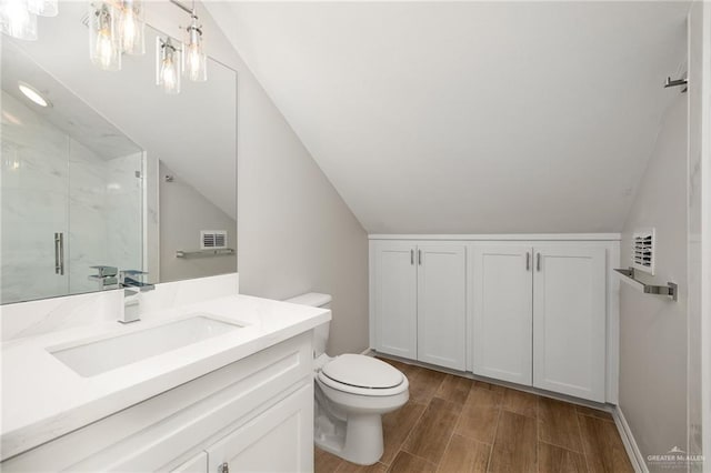 bathroom featuring lofted ceiling, vanity, toilet, and a shower with shower door