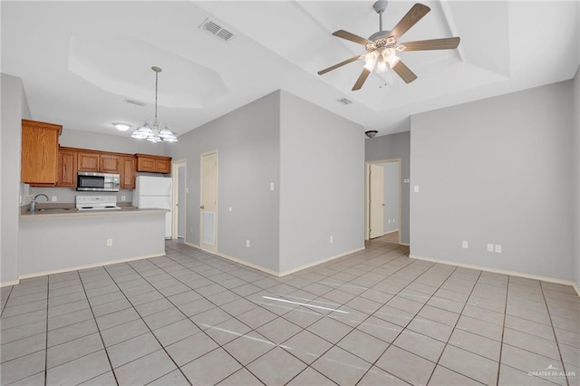 1010 Cedarwood Dr, Rio Grande City, TX 78582 - kitchen with a raised ceiling, stainless steel microwave, a ceiling fan, a peninsula, and brown cabinets