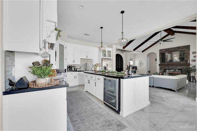 kitchen featuring decorative light fixtures, white cabinets, wine cooler, stainless steel refrigerator with ice dispenser, and a center island with sink