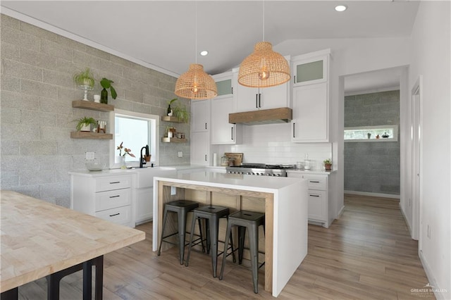 kitchen with a breakfast bar, white cabinets, lofted ceiling, and sink