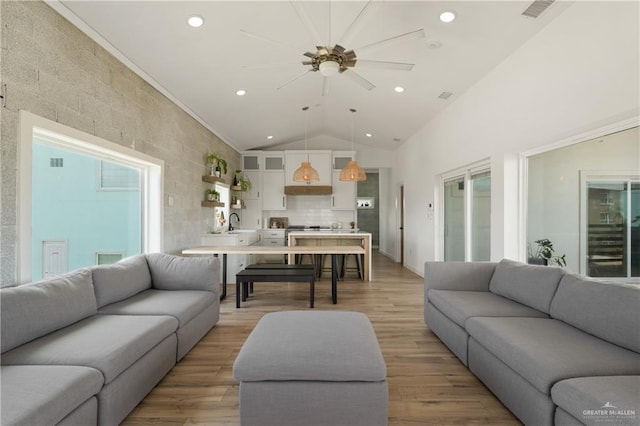 living room with vaulted ceiling, ceiling fan, light hardwood / wood-style floors, and tile walls