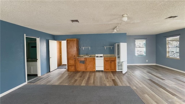 kitchen featuring track lighting, a textured ceiling, sink, hardwood / wood-style flooring, and range