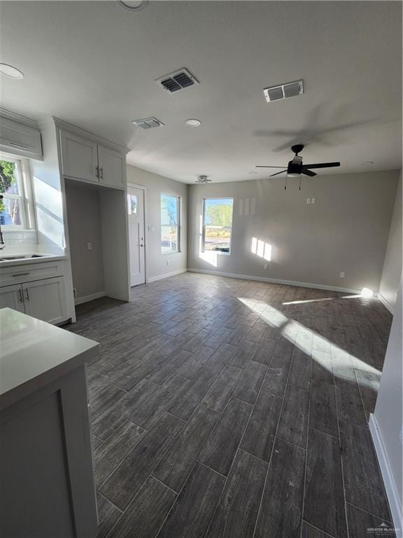 unfurnished living room featuring dark hardwood / wood-style floors, ceiling fan, and sink