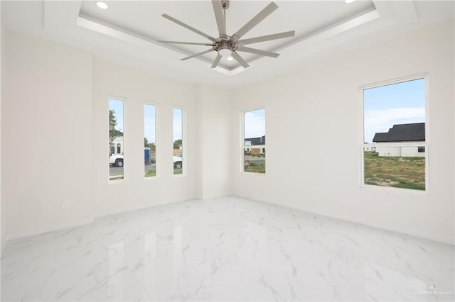 spare room with a raised ceiling, ceiling fan, and a healthy amount of sunlight