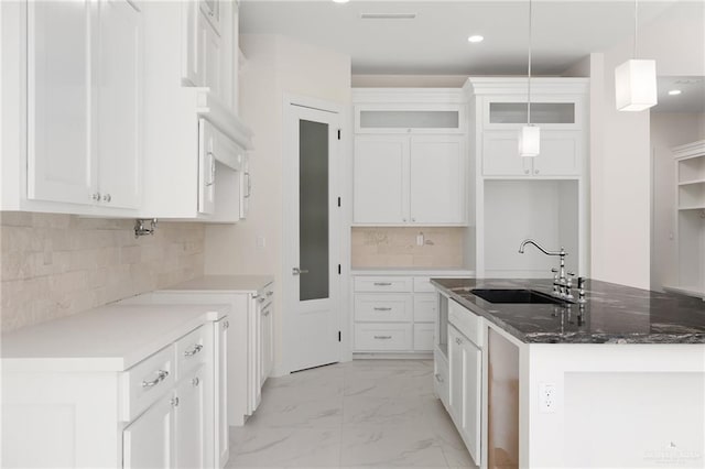 kitchen featuring sink, white cabinetry, hanging light fixtures, and an island with sink