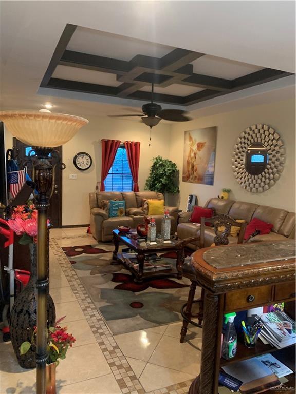 tiled living room with a ceiling fan, coffered ceiling, and beam ceiling