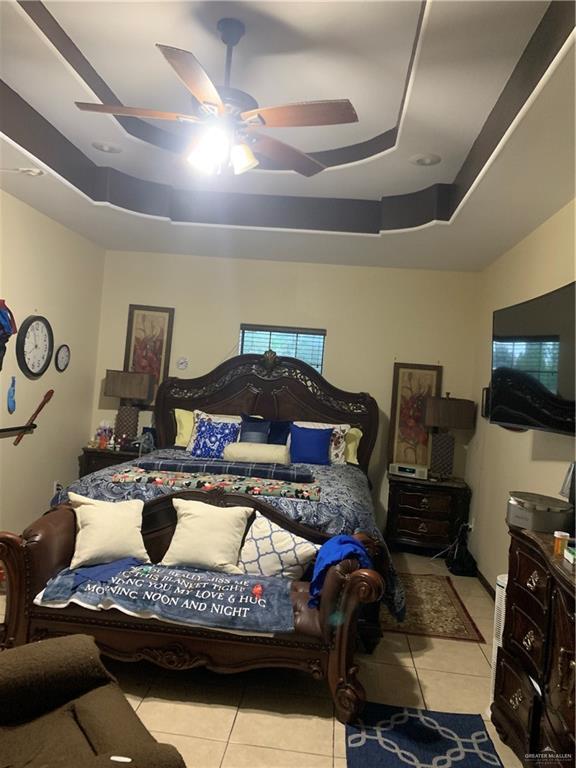 tiled bedroom featuring a ceiling fan and a tray ceiling