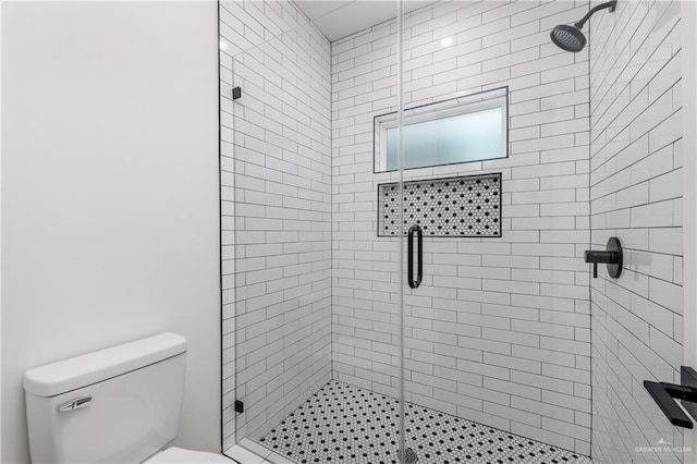 bathroom featuring a shower with shower door and toilet