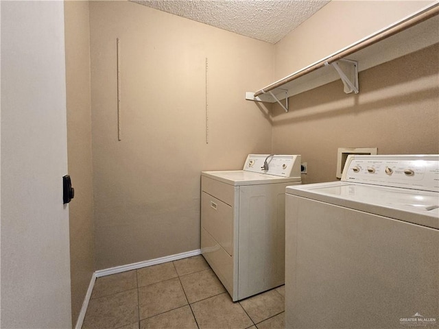 clothes washing area with light tile patterned flooring, a textured ceiling, and washing machine and clothes dryer