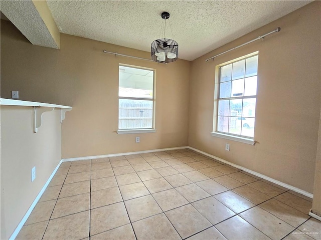 unfurnished dining area with light tile patterned flooring and a textured ceiling