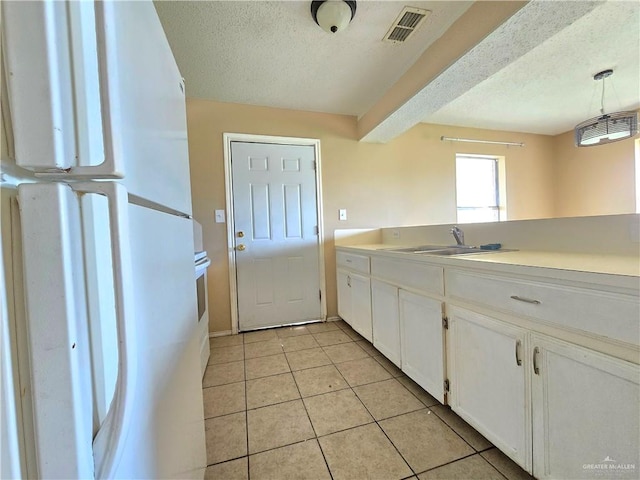 kitchen with white cabinetry, sink, white refrigerator, decorative light fixtures, and light tile patterned floors