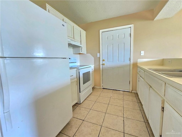 kitchen featuring white appliances, a textured ceiling, sink, light tile patterned floors, and white cabinets