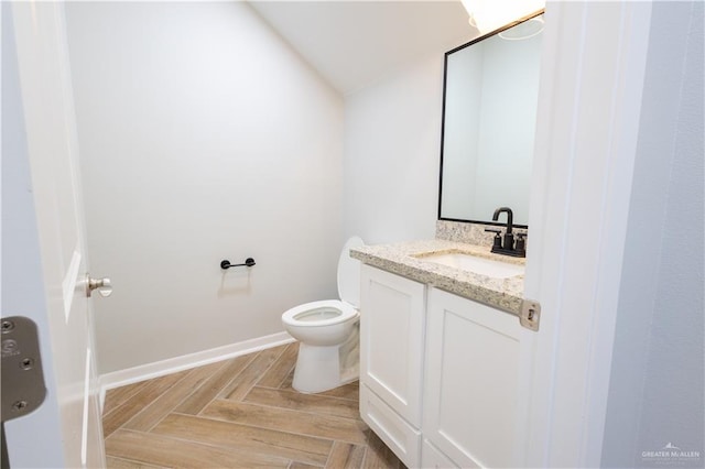 bathroom featuring vanity, toilet, and parquet flooring