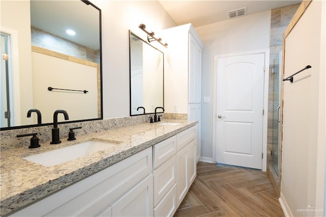 bathroom with an enclosed shower, vanity, and parquet floors