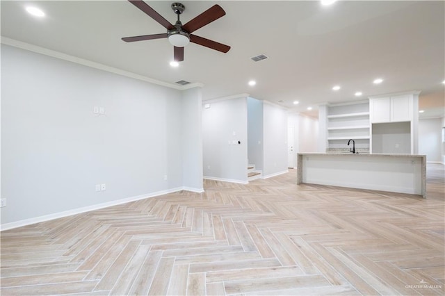 unfurnished living room with ceiling fan, sink, crown molding, and light parquet flooring