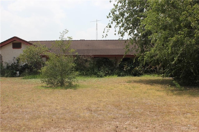 view of front facade featuring a tiled roof and a front lawn