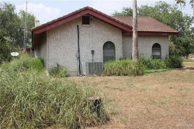 view of home's exterior featuring stucco siding, a tiled roof, and central AC