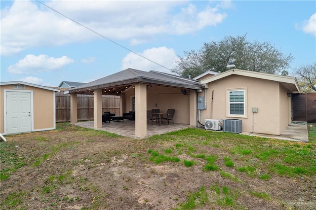 rear view of property featuring a storage unit, ac unit, a yard, central AC unit, and a patio area